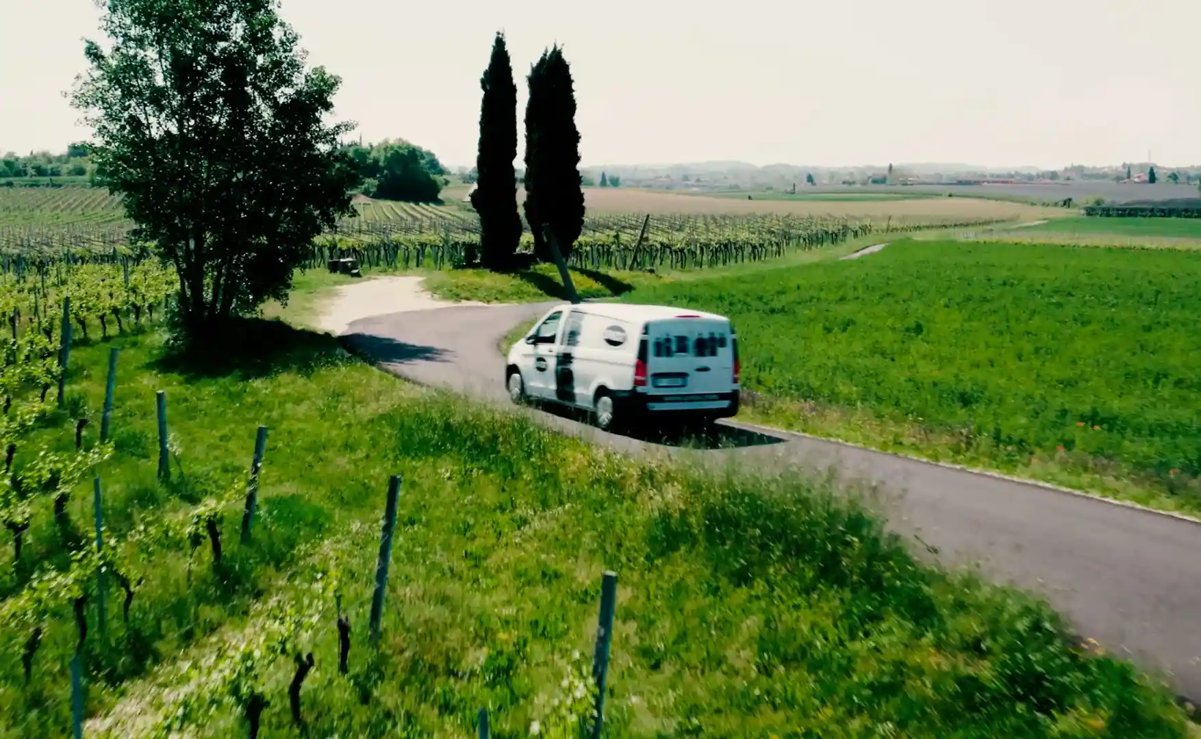 Uma chef abre a porta de um forno combinado Unox, com um chef ao seu lado na cozinha. Legumes e ervas estão sobre uma tábua de corte no balcão.